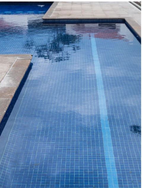 Piscina revestida de gresite azul oscuro con franja de color más claro en el fondo
