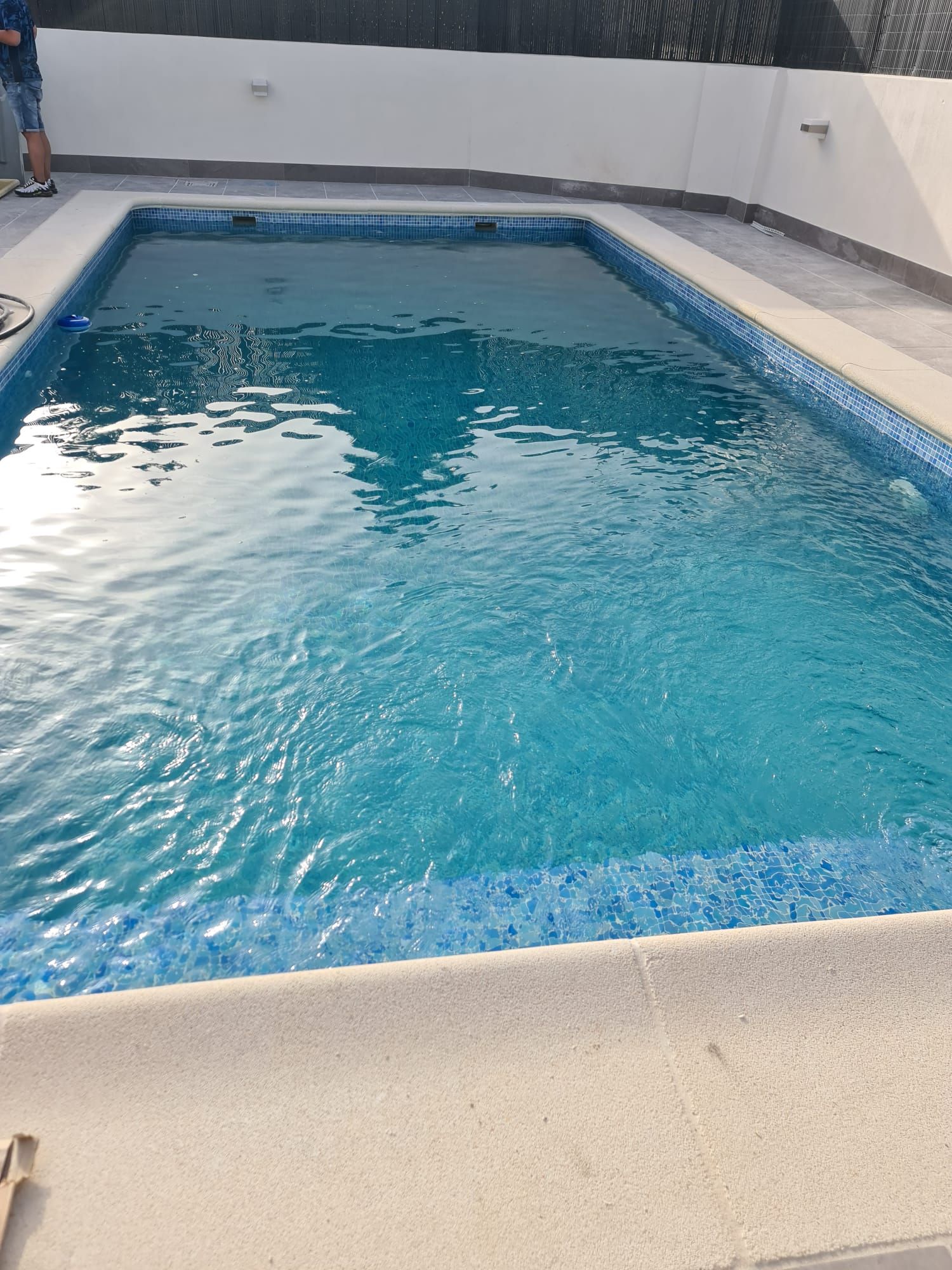 Detalle del agua cristalina sobre el gresite azul de una piscina