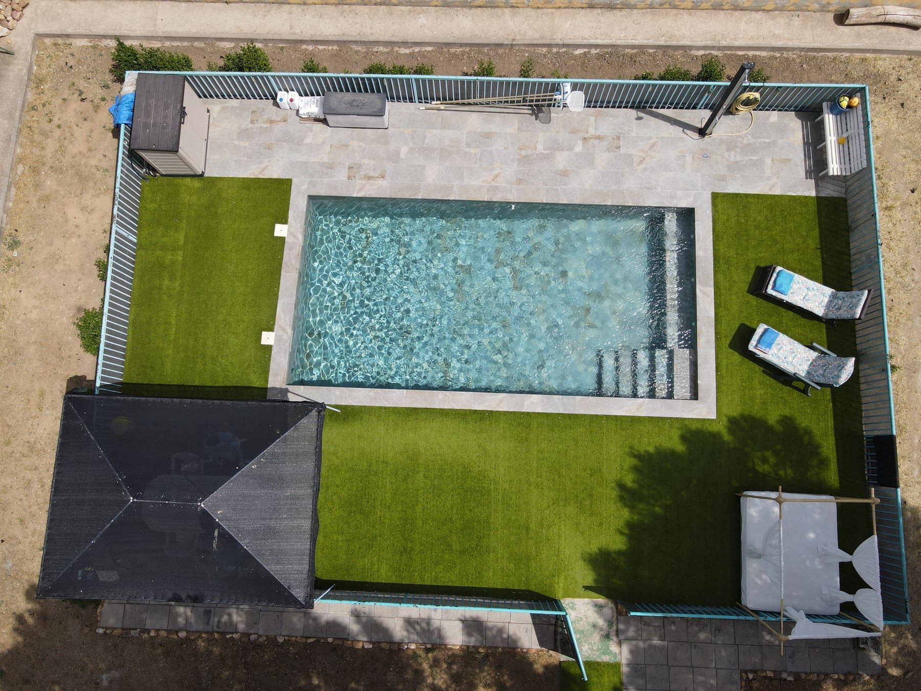 Piscina alargada con chorro y escalera de obra, vista cenital con dron