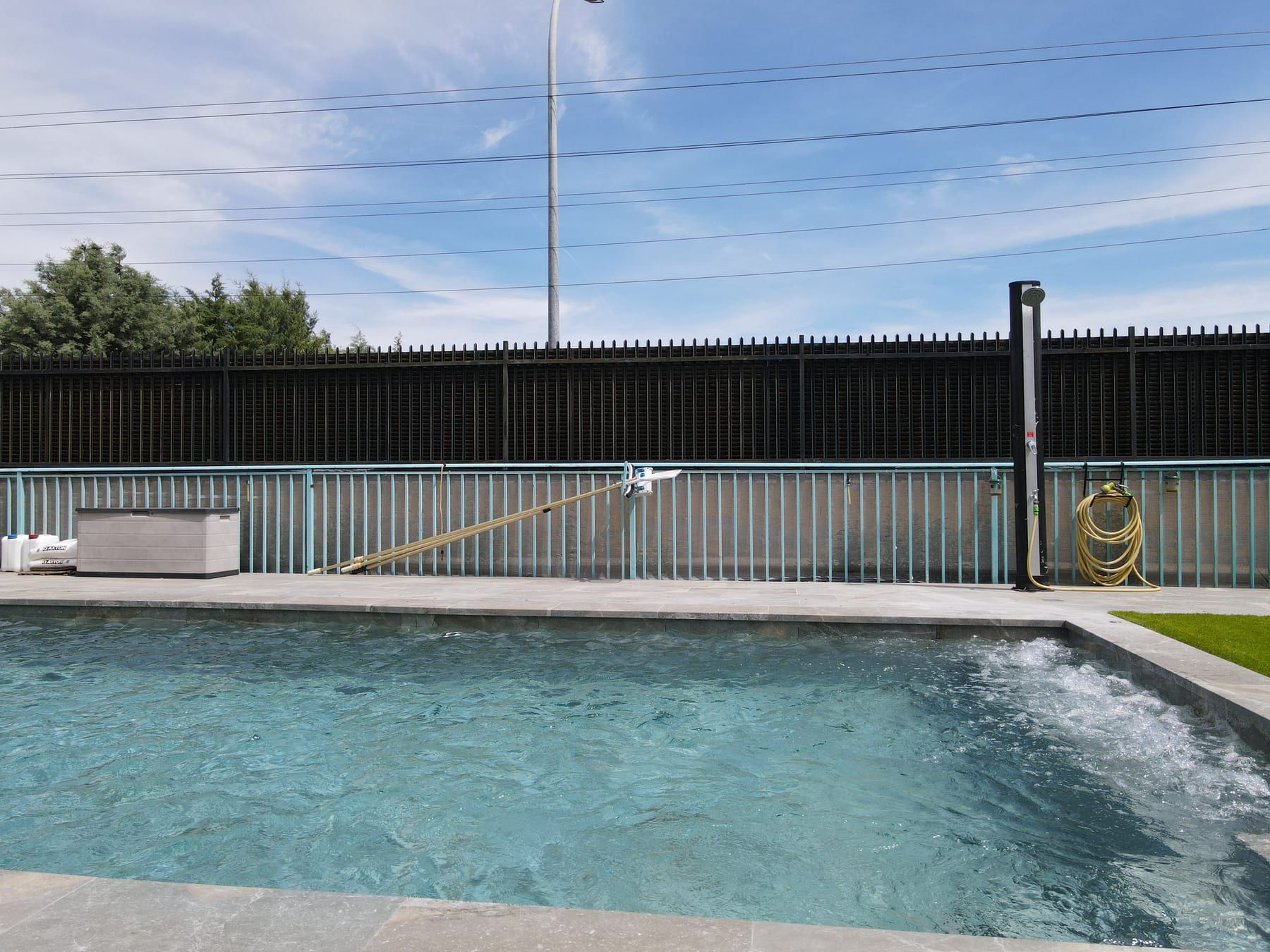 Piscina alargada con chorro y escalera de obra, con el chorro de pared, vista con dron