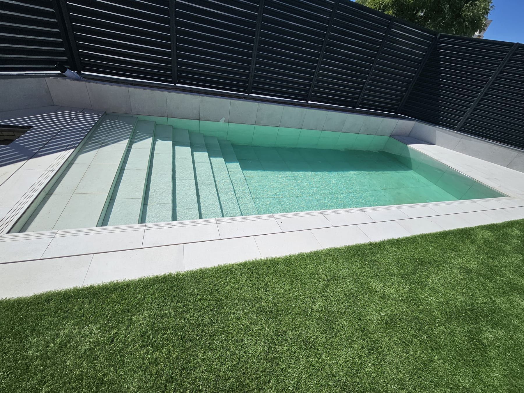 Piscina alargada con escalera de obra de ancho completo, con la escalera de obra de ancho completo