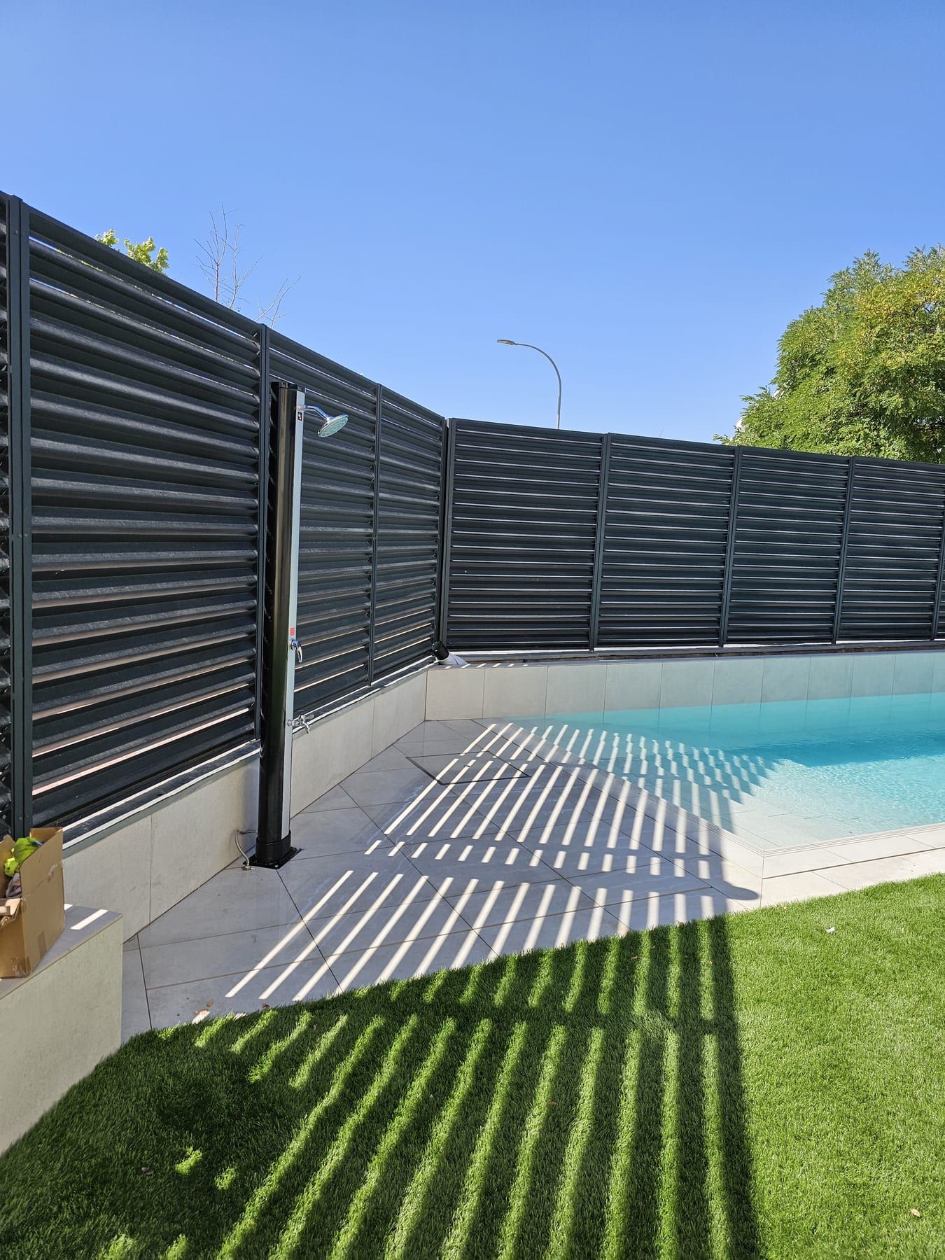 Piscina alargada con escalera de obra de ancho completo, con la ducha exterior
