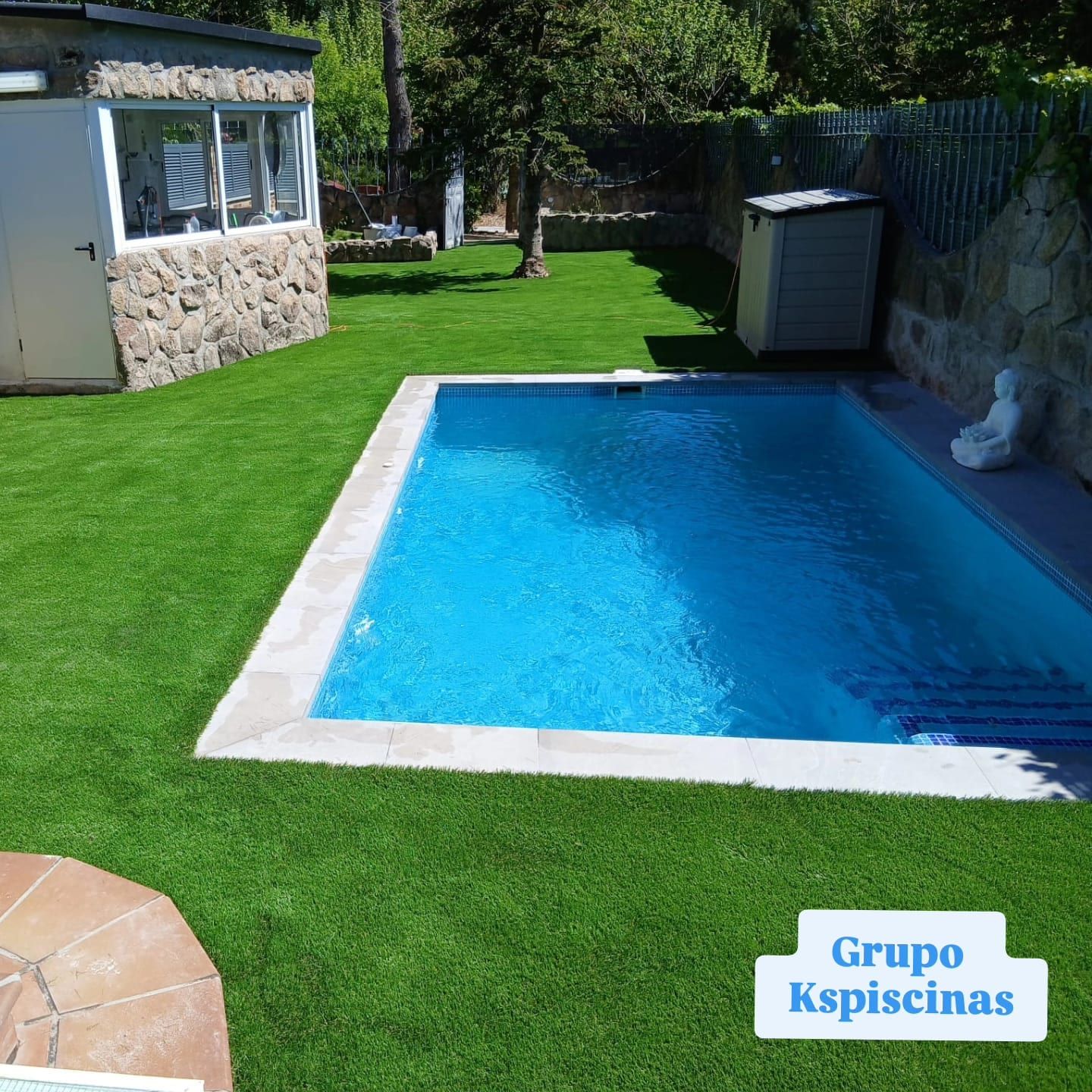 Piscina azul en jardín con muro de piedra