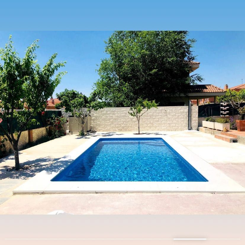 Piscina azul en patio con pavimento claro