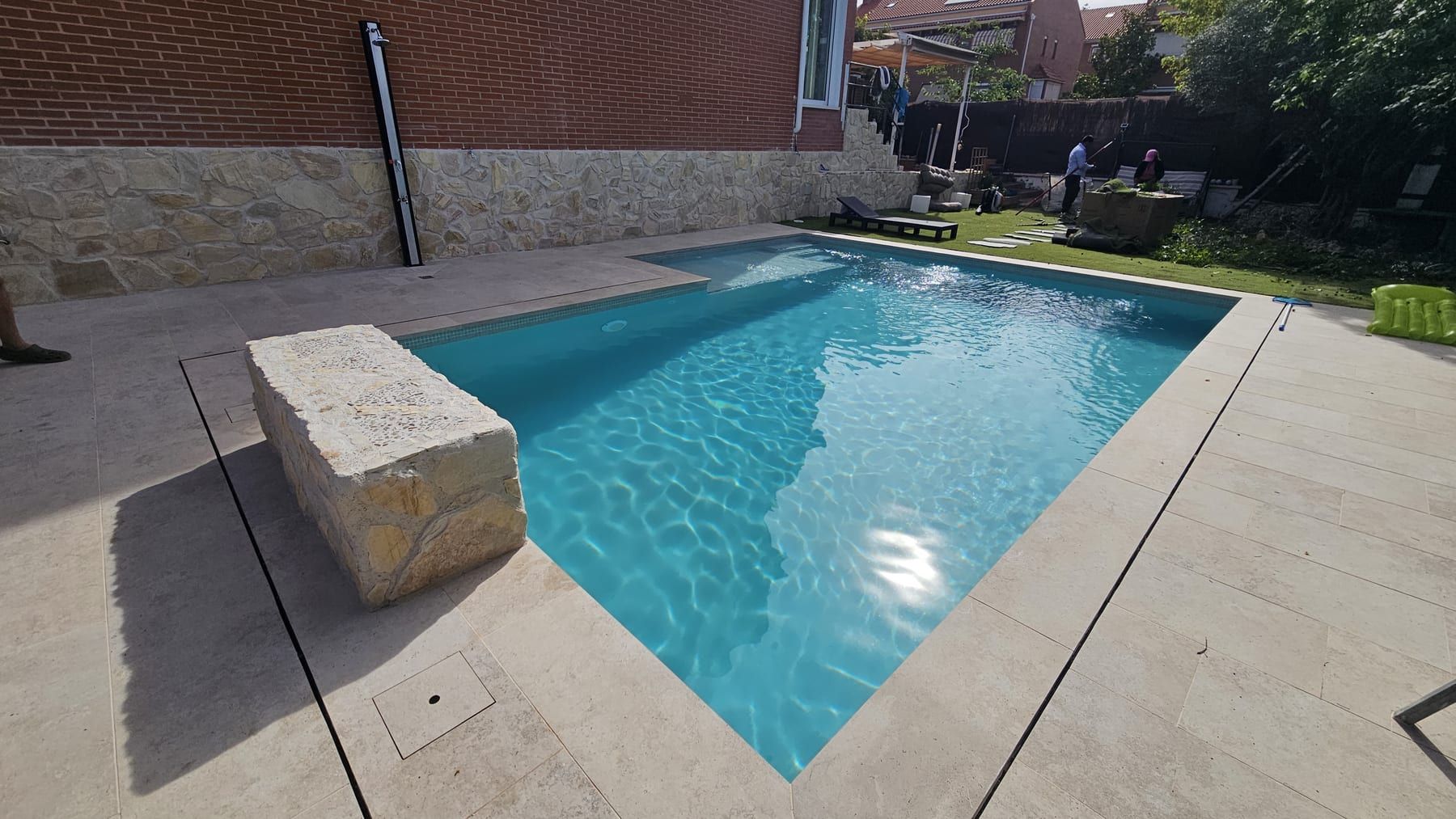 Piscina con banco de piedra junto a casa de ladrillo