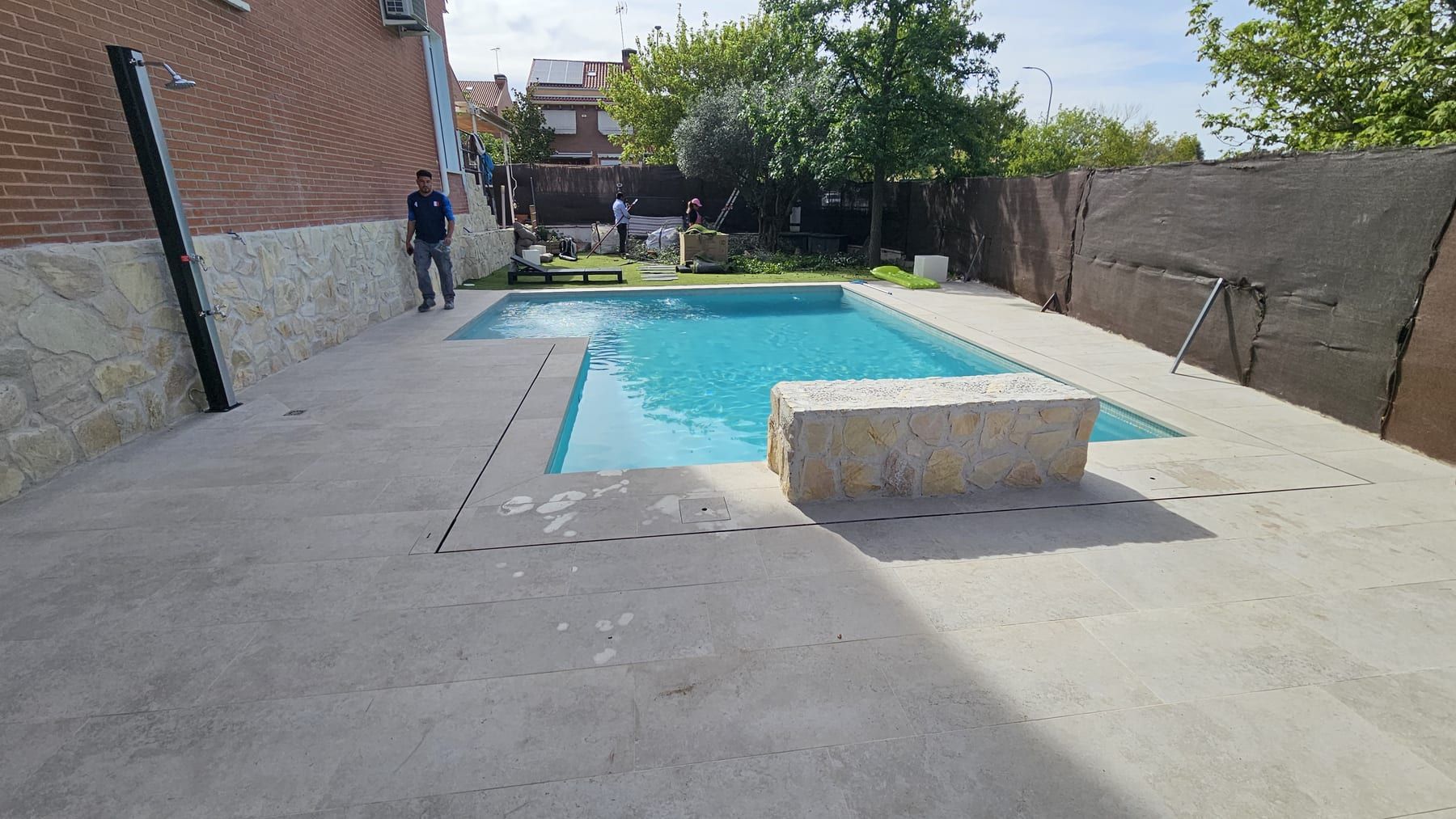 Piscina con banco de piedra junto a casa de ladrillo, vista 2