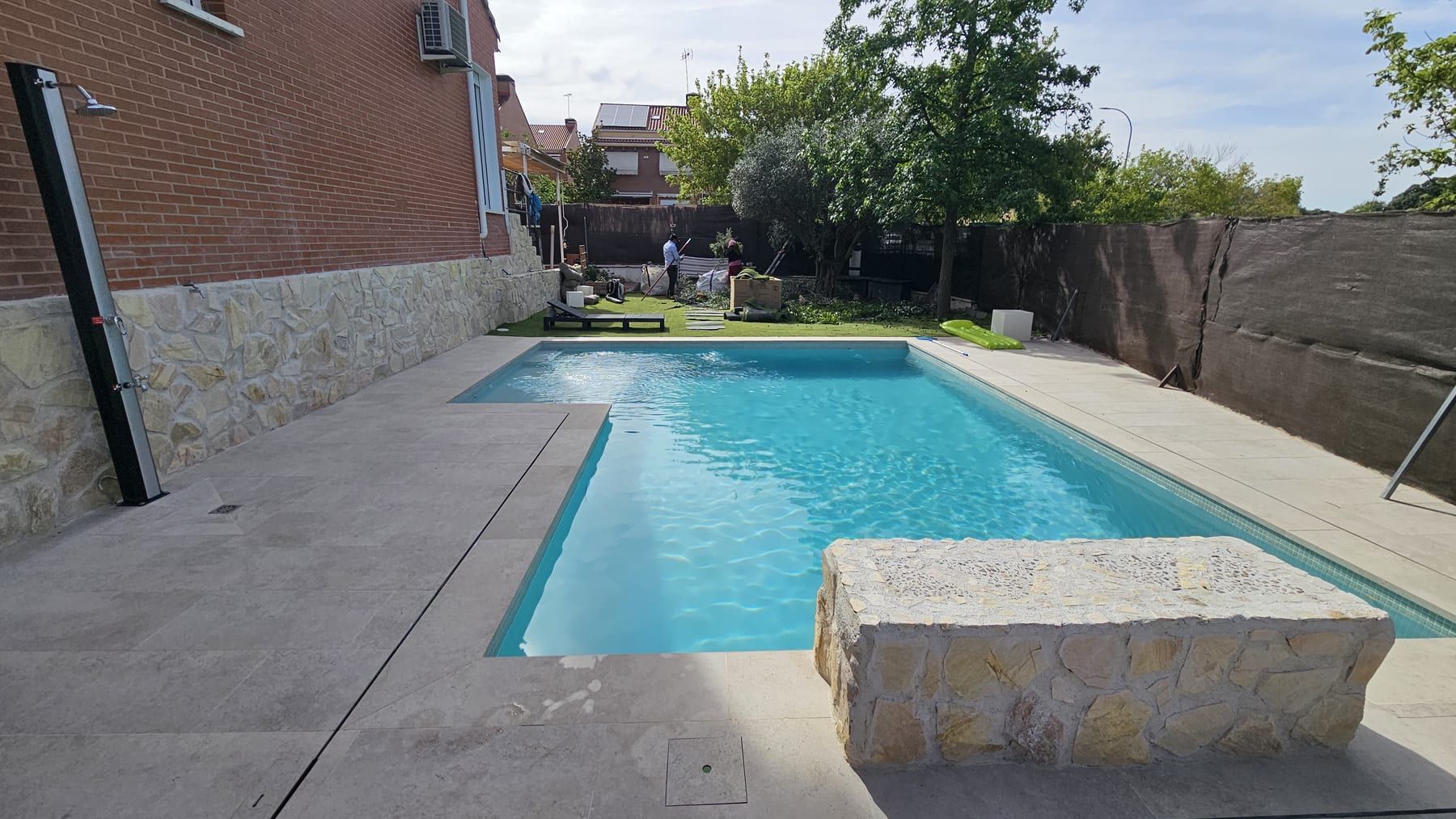 Piscina con banco de piedra junto a casa de ladrillo, vista 3