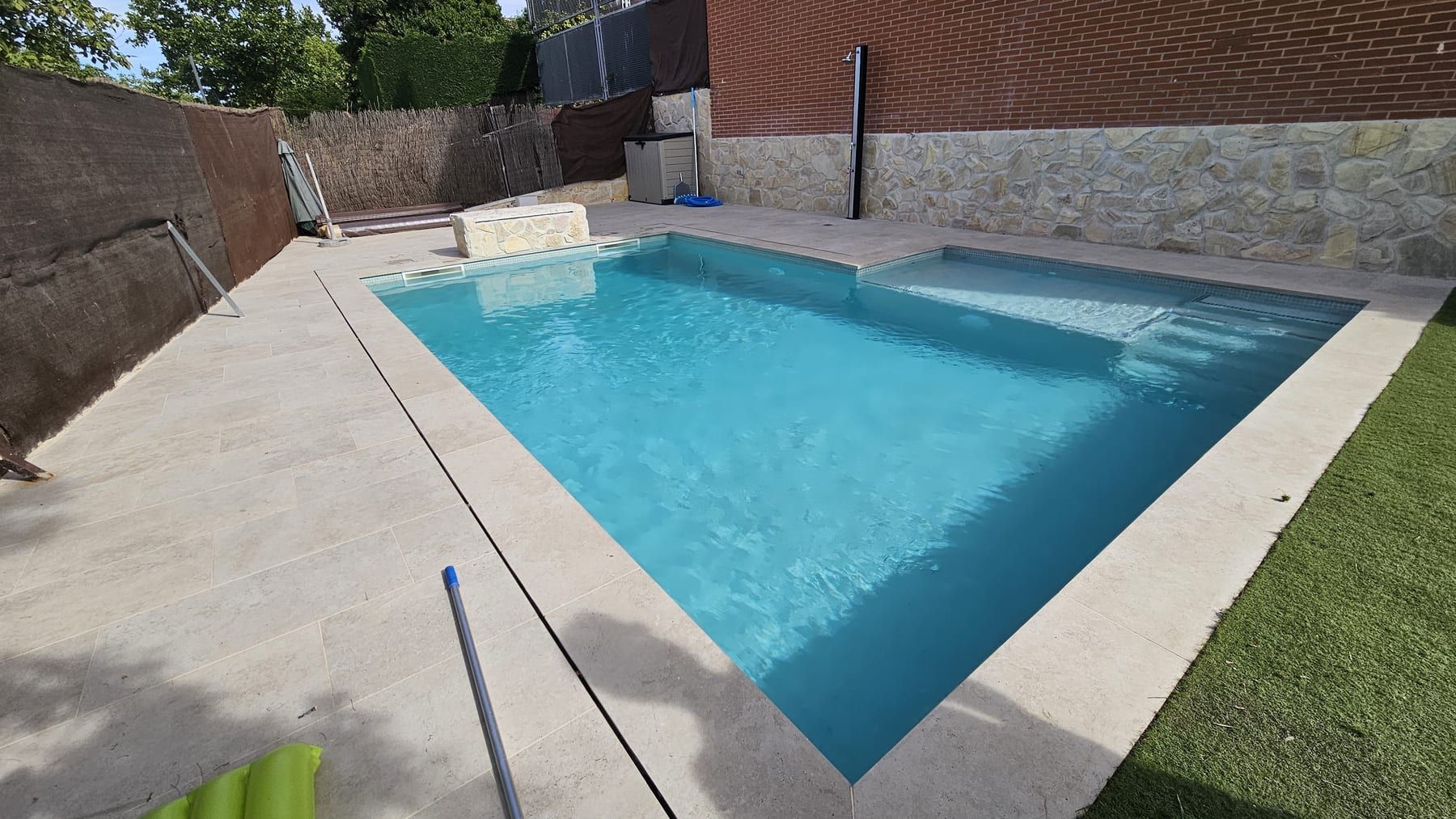 Piscina con banco de piedra junto a casa de ladrillo, vista 4