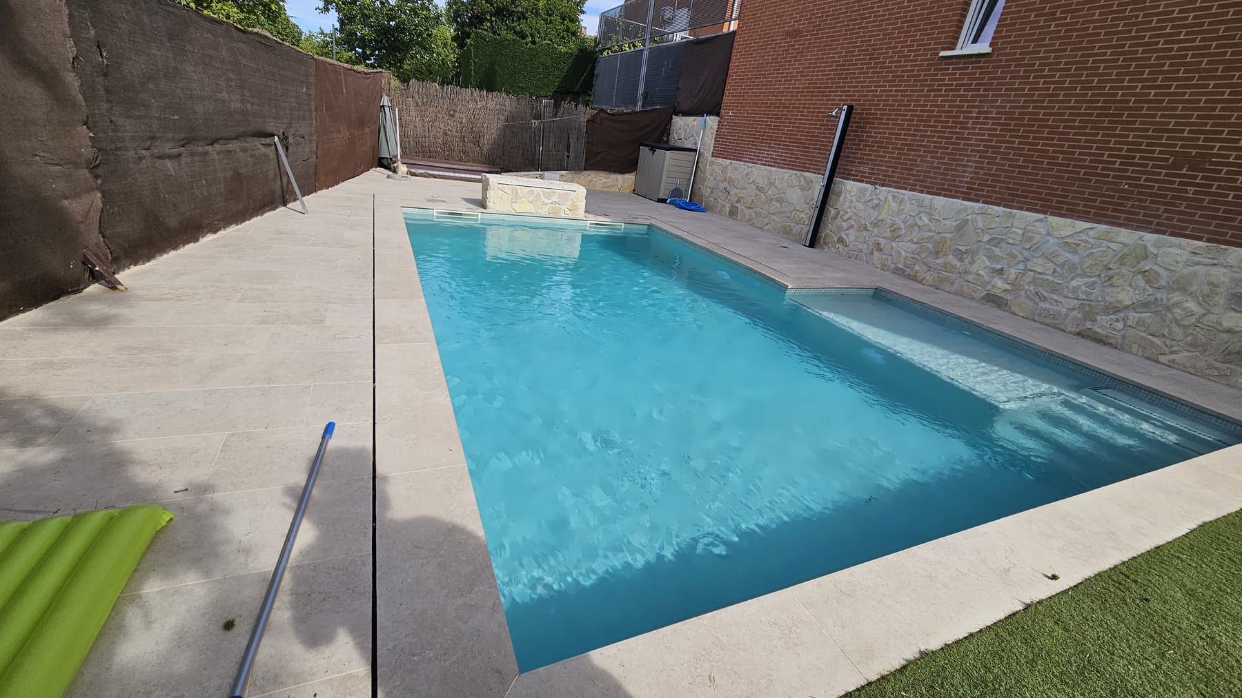 Piscina con banco de piedra junto a casa de ladrillo, vista 5