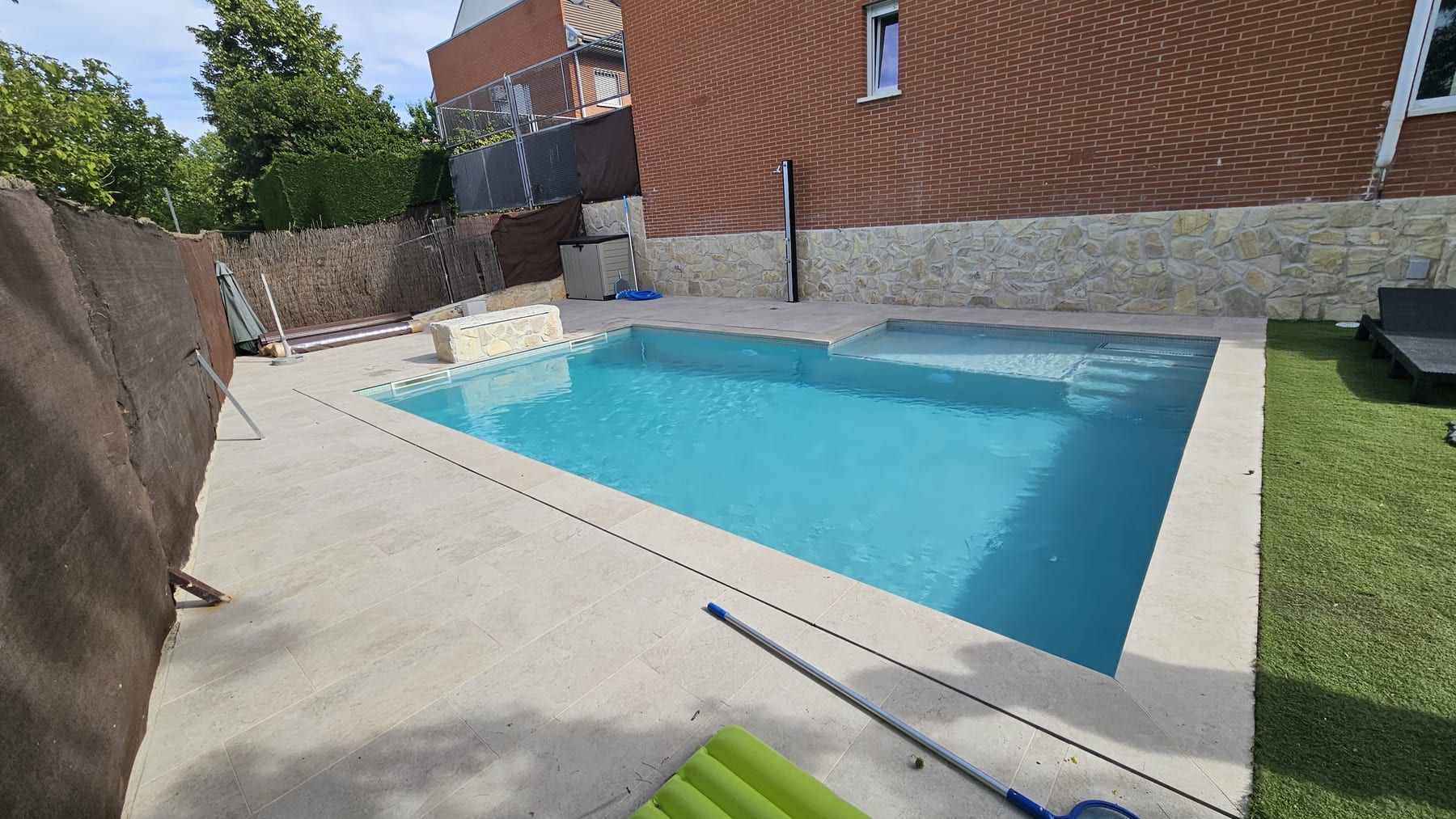 Piscina con banco de piedra junto a casa de ladrillo, vista 6
