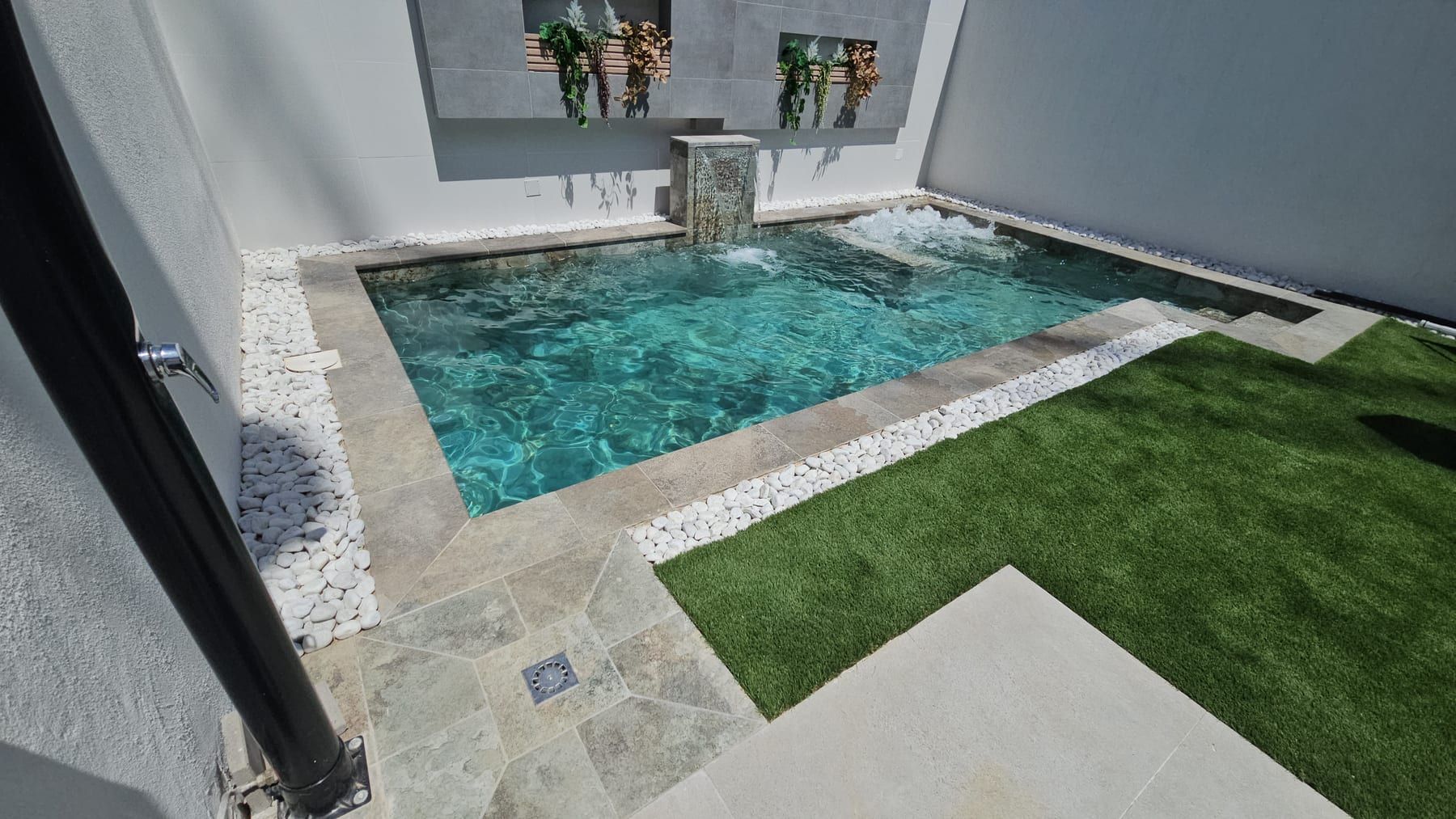 Piscina con cascada y muro blanco con jardineras, vista 3