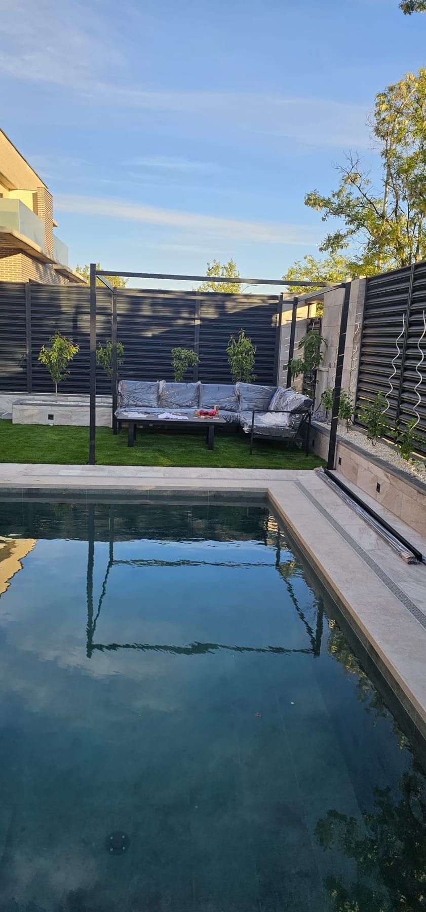 Piscina con zona chill-out junto a valla de lamas