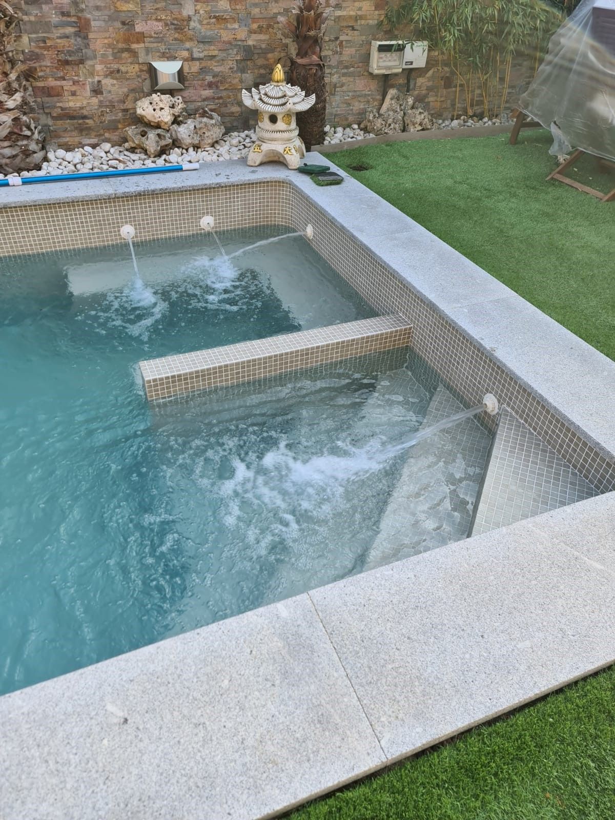 Piscina de agua clara con chorros de pared en funcionamiento y escalón interior