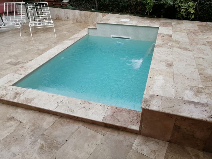 Piscina de gresite claro con coronación y solado de piedra natural