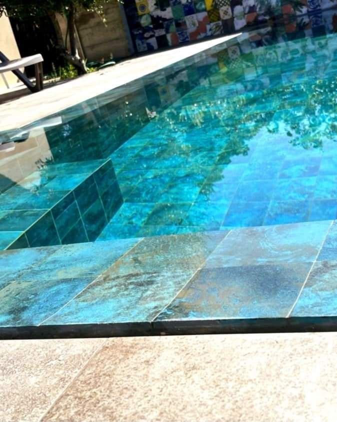 Piscina desbordante con porcelánico verde, con el efecto espejo del desbordante