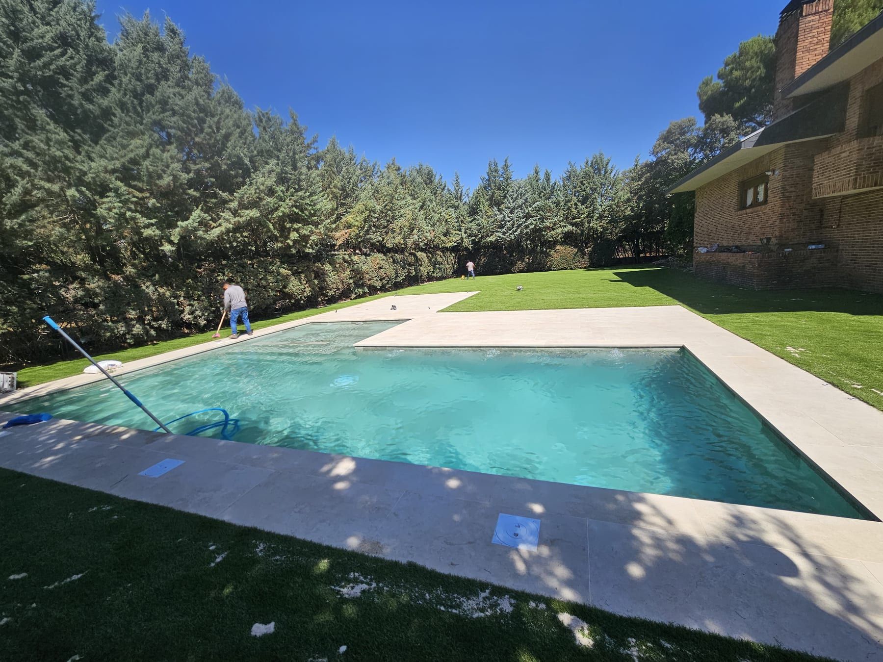 Piscina en L con gran playa en jardín amplio, vista 2