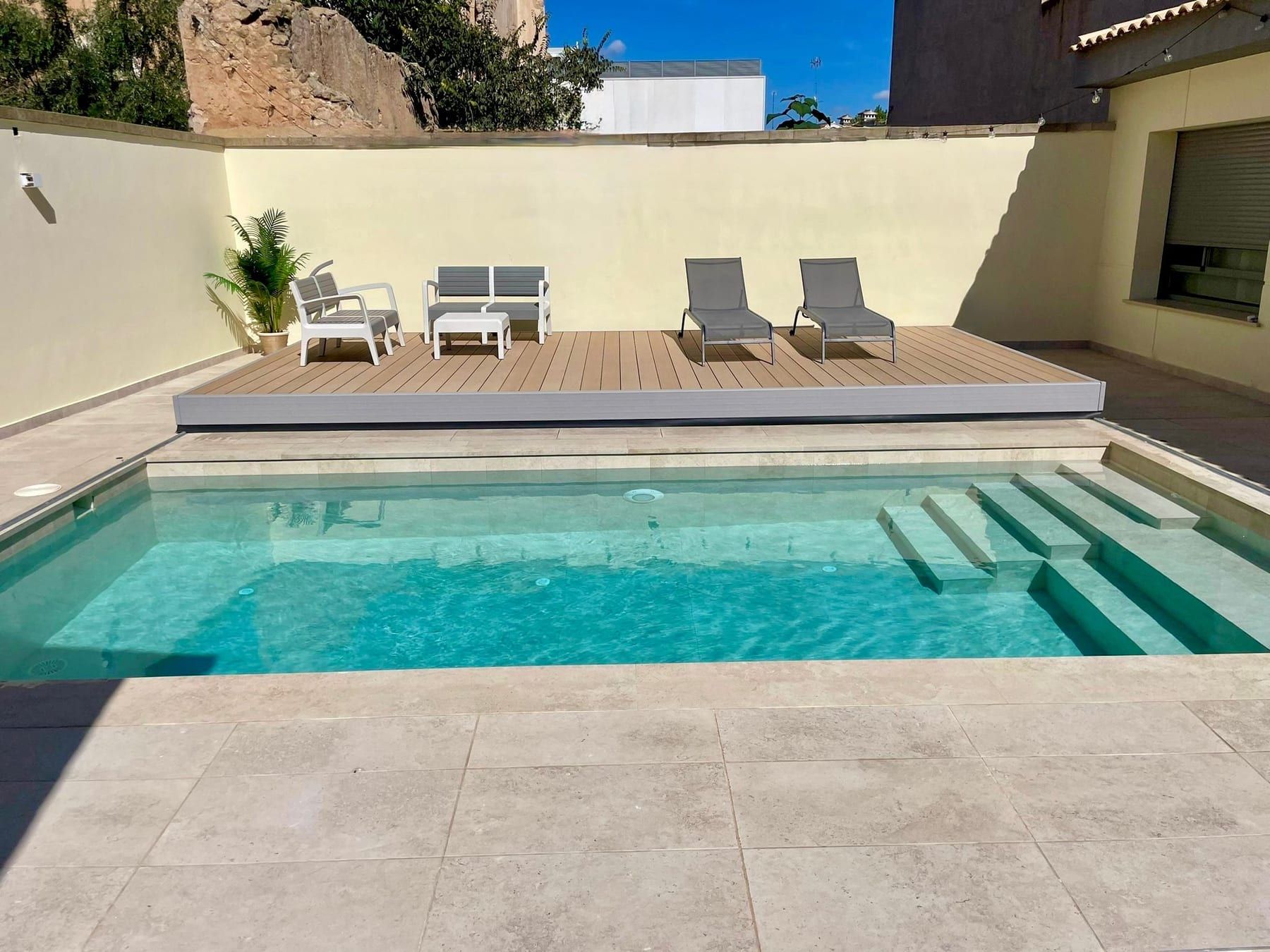 Piscina con escalera de obra y tarima en patio
