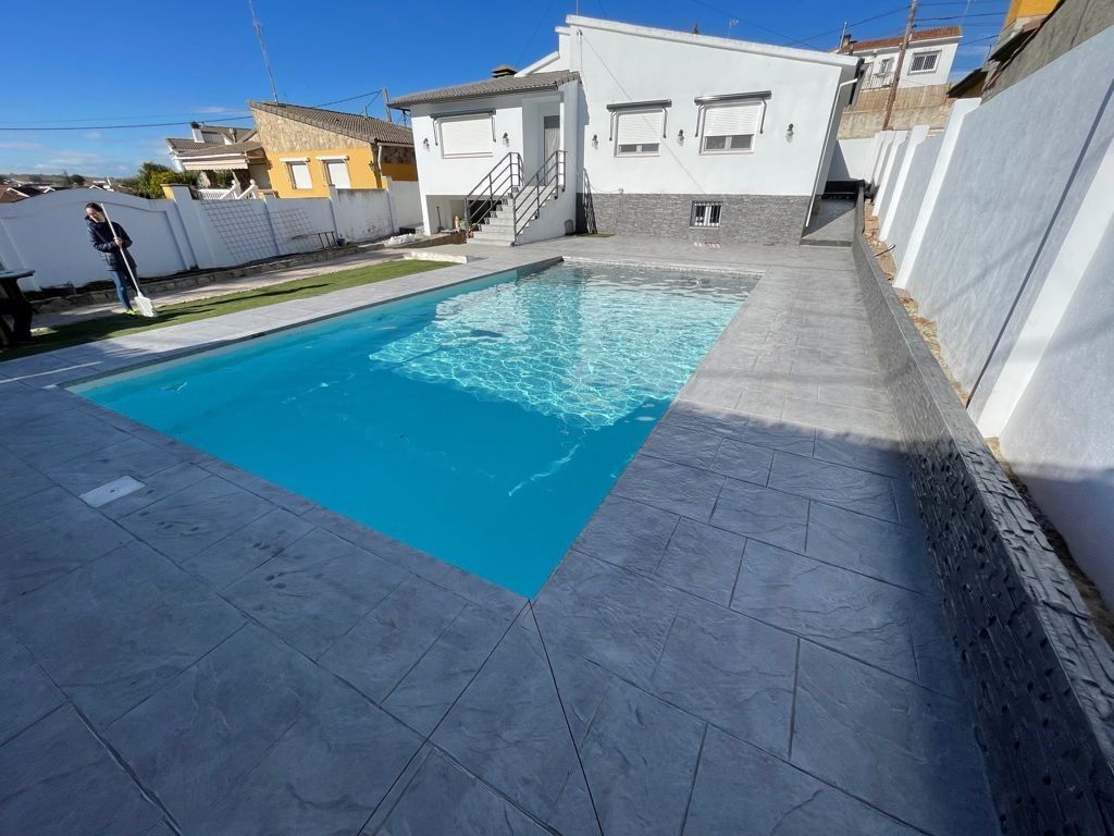 Piscina de gresite blanco en un patio con pavimento exterior gris