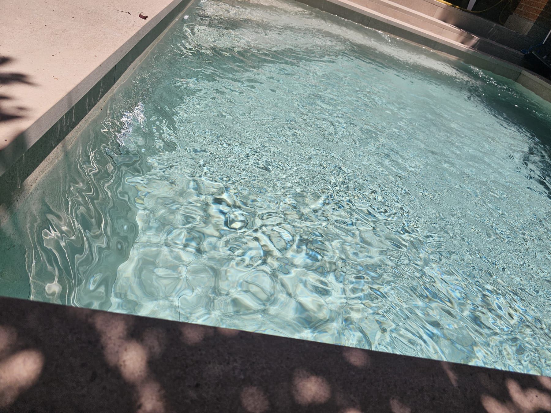 Piscina en tonos gris verdoso con chorro de pared, vista 4