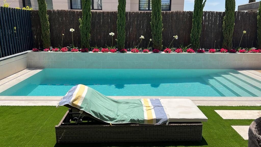 Piscina con escalera de ancho completo y jardín de flores