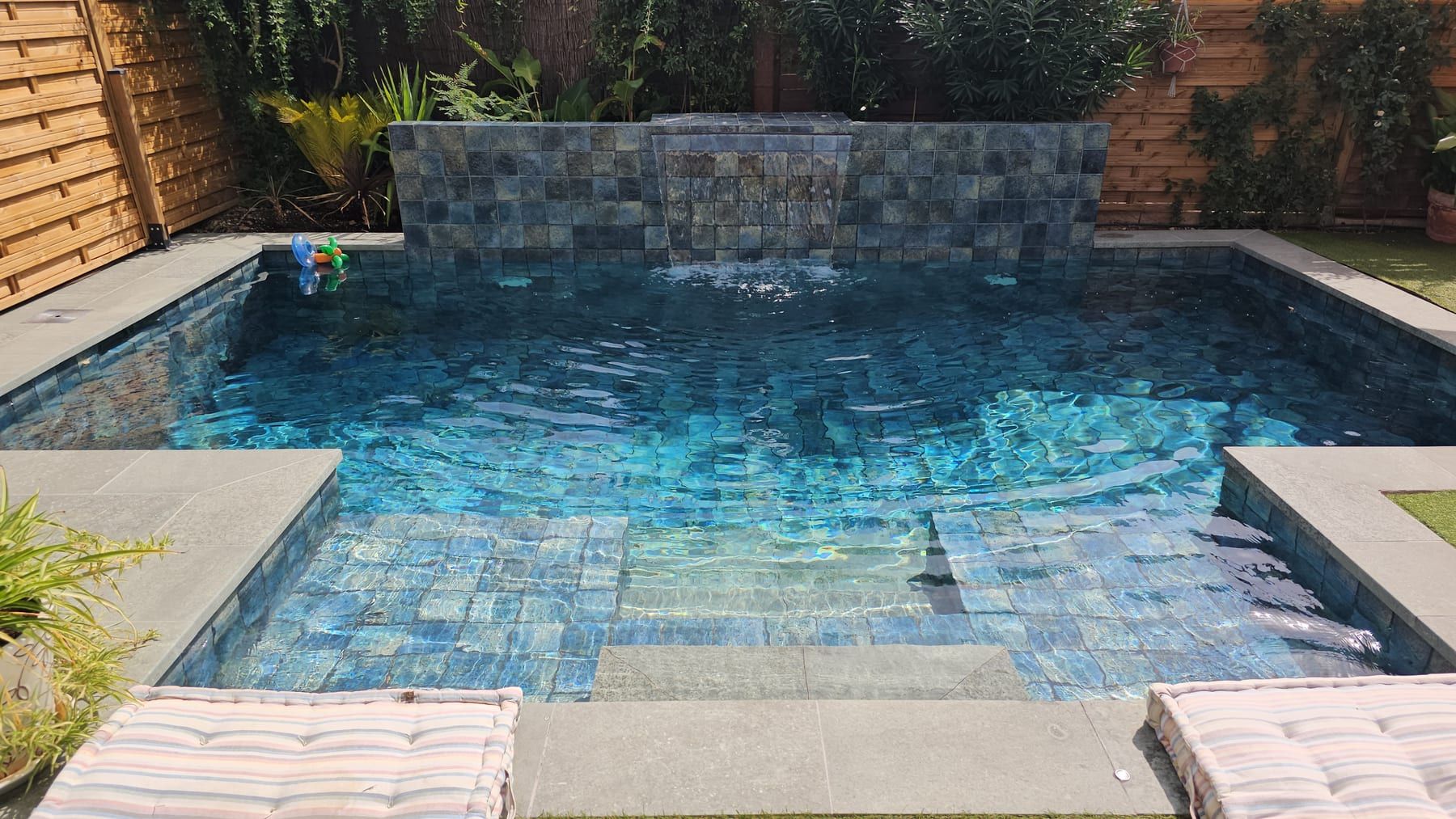 Piscina con muro de piedra y cascada, con la cascada en funcionamiento