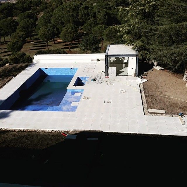 Vista elevada de una piscina de obra con escalera y pavimento exterior recién terminado