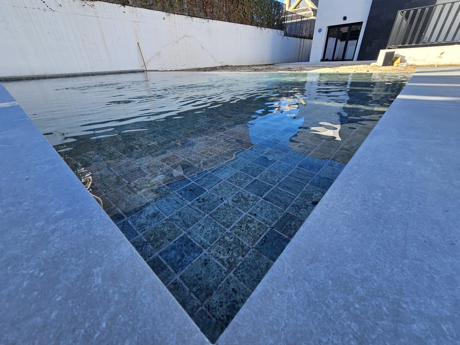 Piscina con porcelánico verde y coronación gris