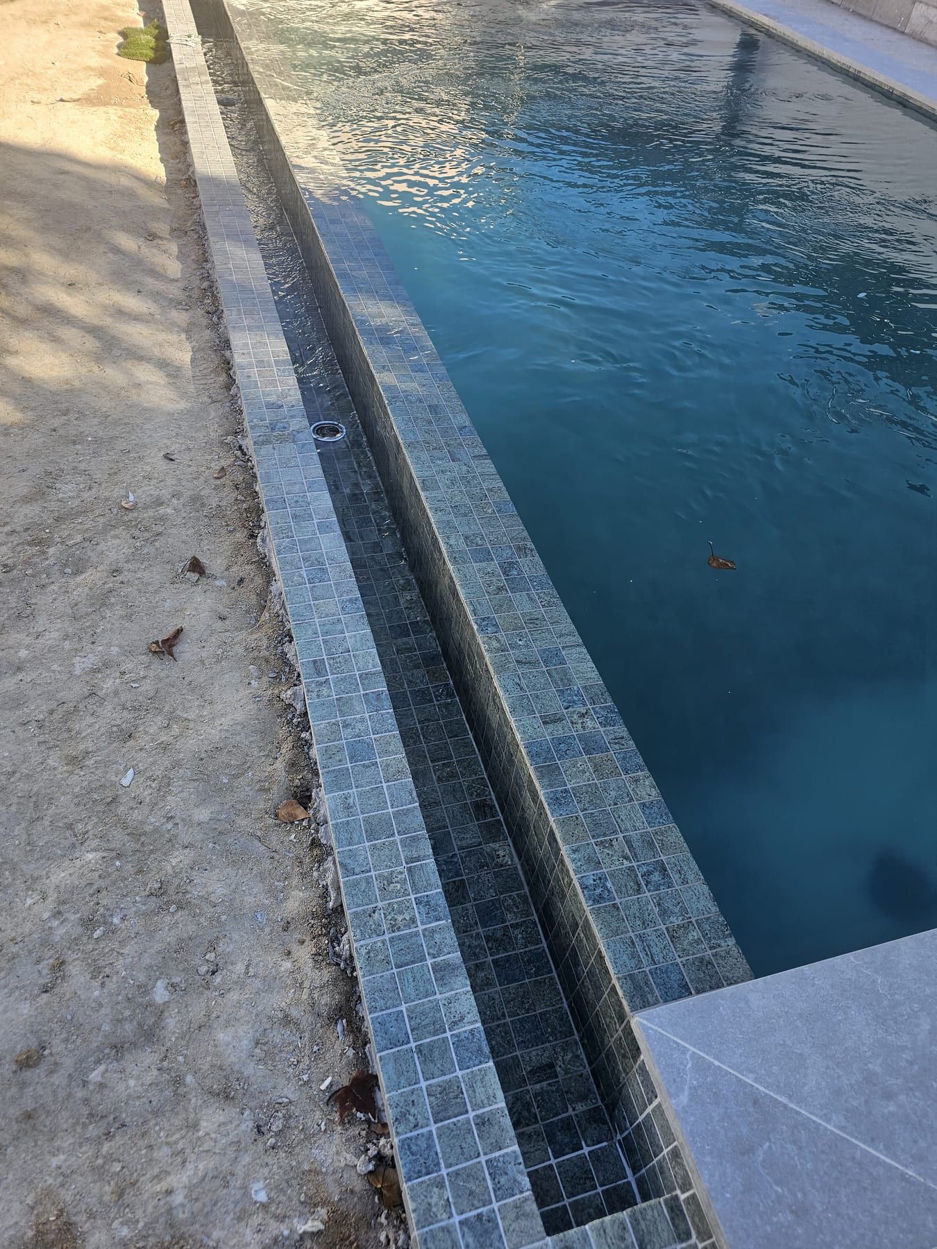 Piscina con porcelánico verde y coronación gris, detalle del borde