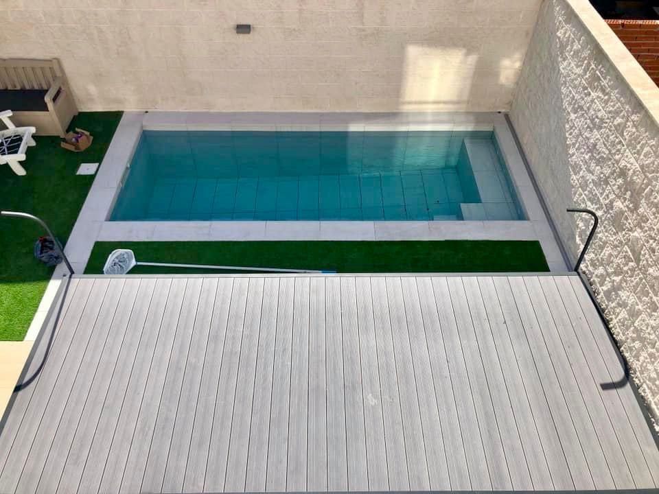 Piscina con tarima y muro de piedra blanca